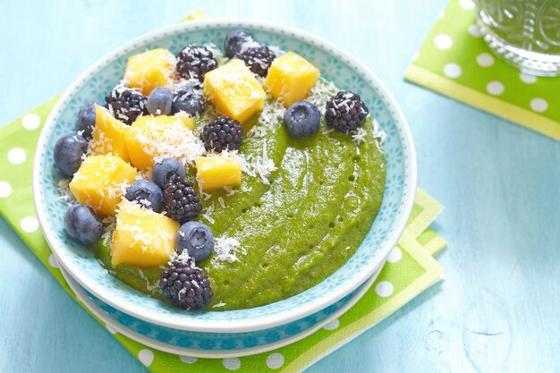 Breakfast green smoothie bowl topped with fruits