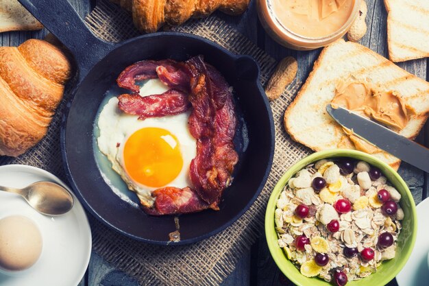 Breakfast including fried egg croissant orange juice muesli and bread