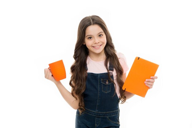 Breakfast is fuel for school Schoolgirl having school breakfast in morning Cute school child holding cup and note book Little kid drinking morning tea or milk Small girl enjoying her school meal