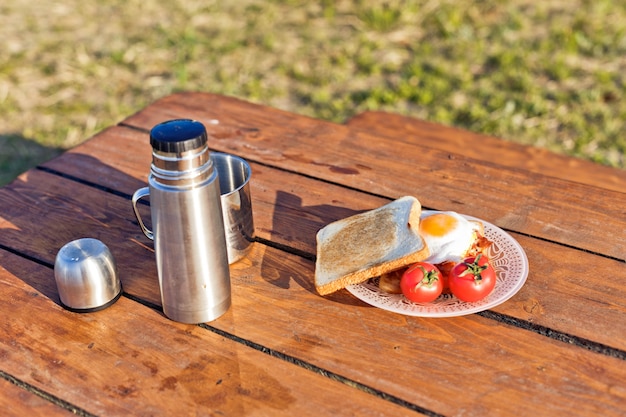 Breakfast in nature Fried eggs with bacon fried toast and hot coffee from a thermos
