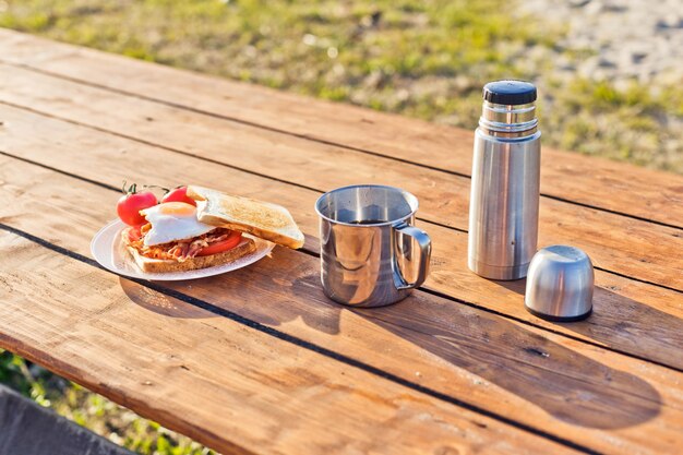 자연 속에서의 아침 식사 베이컨 튀김 토스트와 보온병의 따뜻한 커피를 곁들인 계란 후라이