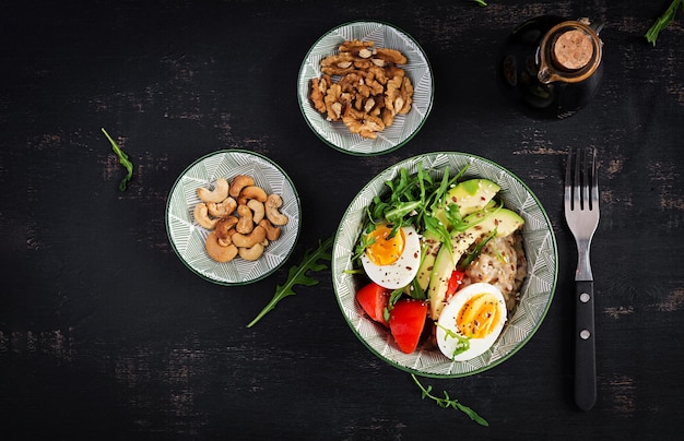 Porridge di farina d'avena per la colazione con uova sode pomodori avocado ed erbe verdi cibo sano ed equilibrato vista dall'alto piatto