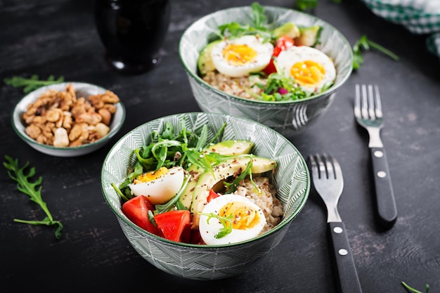 Porridge di farina d'avena per la colazione con uova sode pomodori avocado ed erbe verdi cibo sano ed equilibrato