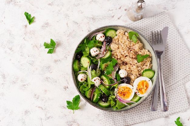 Breakfast oatmeal porridge with boiled eggs cucumber mozzarella cheese and green herbs Healthy balanced food Top view