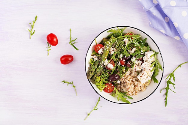 Porridge di farina d'avena per la colazione con formaggio feta pomodorini asparagi e rucola cibo sano ed equilibrato vista dall'alto