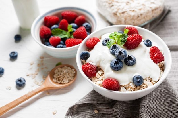 Breakfast, oatmeal with blueberry and raspberry on white bowl in the morning.