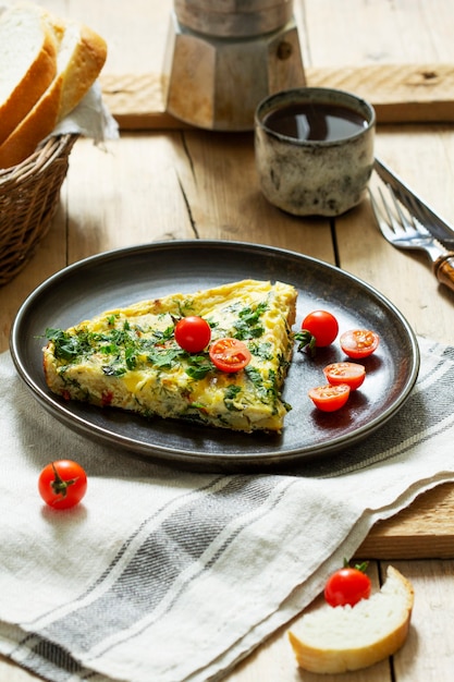 Breakfast of omelet with vegetables, herbs and cheese, served with bread and coffee.