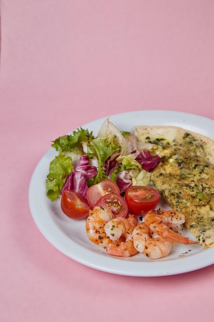 Breakfast plate scrambled eggs with shrimps and tomatoes on monochromatic delicate background side view