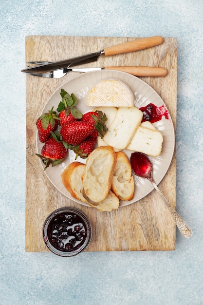 Фото Тарелка для завтрака с сыром, хлебом, клубникой и джемом