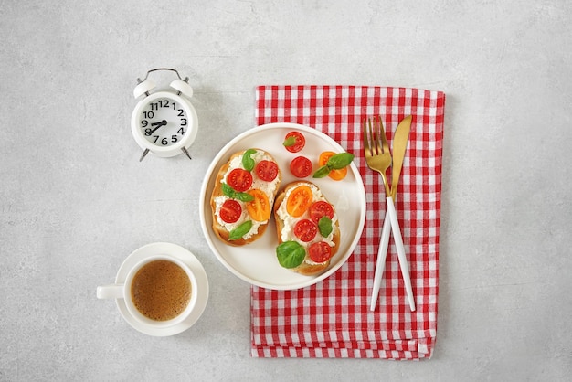 チーズとトマトの朝食サンドイッチ 一杯のコーヒーと目覚まし時計 ブルスケッタまたは健康的なスナックのアイデア トップ ビュー