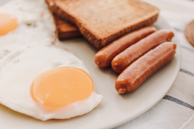 Breakfast set of fried eggs toasted bread sausages and tuna spread