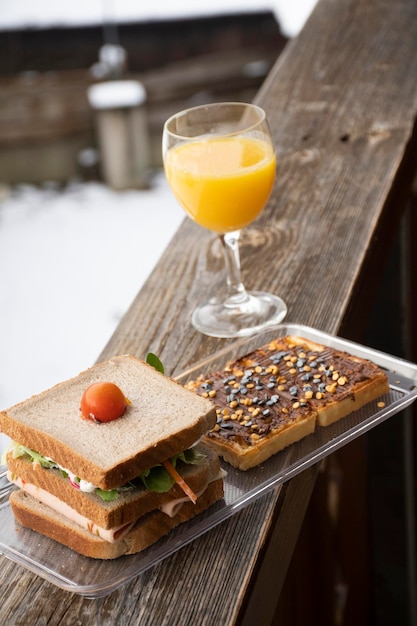 Завтрак на снегу с бутербродом с апельсиновым соком и блинчиком с кремом из фундука