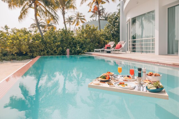 Breakfast in swimming pool, floating breakfast in tropical resort. Table relaxing in calm pool water