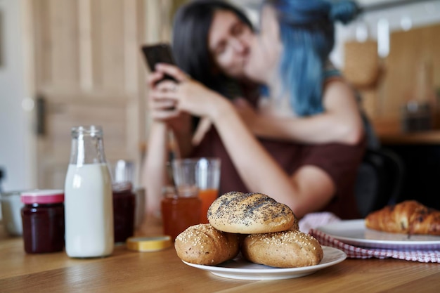 Breakfast on the table and lesbians kissing in the background