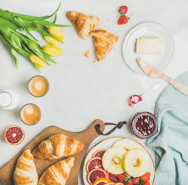 Breakfast table with coffee milk pasrties jam and yellow tulips