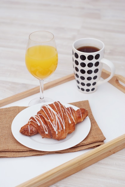 Breakfast. Tea cup, croissant and glass of juice. 