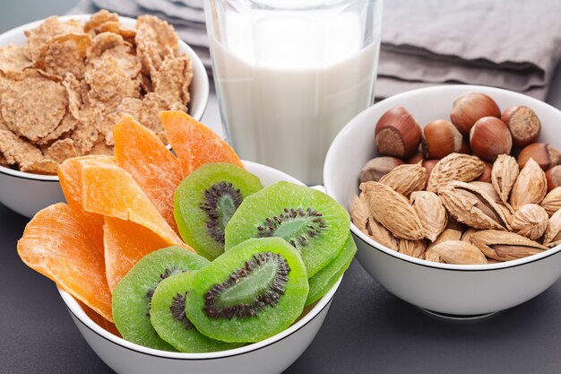 Breakfast Three bowls of nuts cornflakes dried kiwi and mango A glass of milk Healthy eating