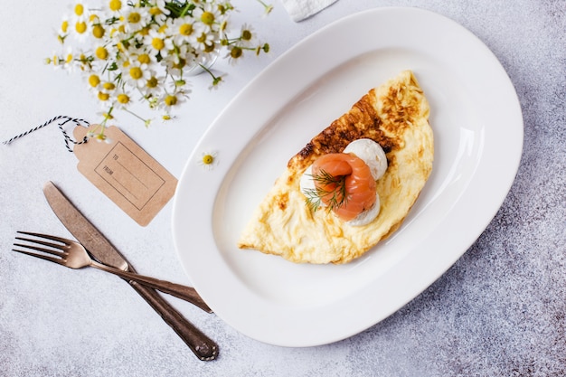 Ora di colazione. frittata con pesce rosso e margherite in un vaso su un tavolo grigio chiaro