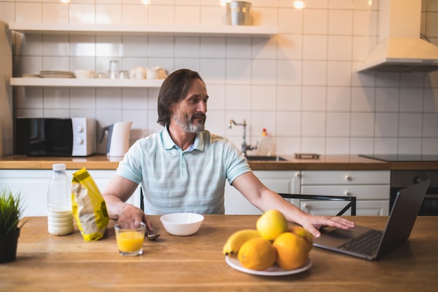 Breakfast time. Single man having breakfast in the kitchen at home