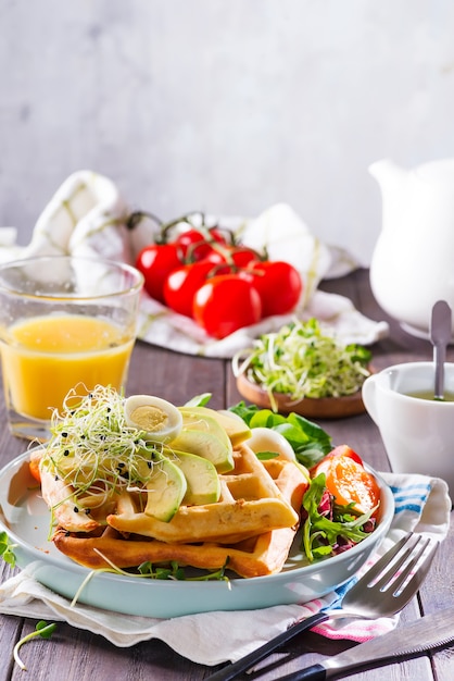 Breakfast time. Waffle with salad, egg, juice and avocados for breakfast