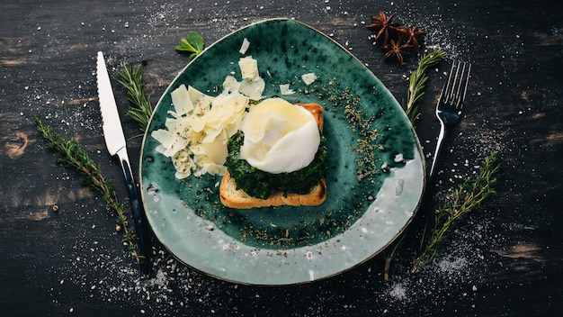 Breakfast Toast Bread with Spinach Poached Egg and Parmesan Cheese On a black wooden background Copy space