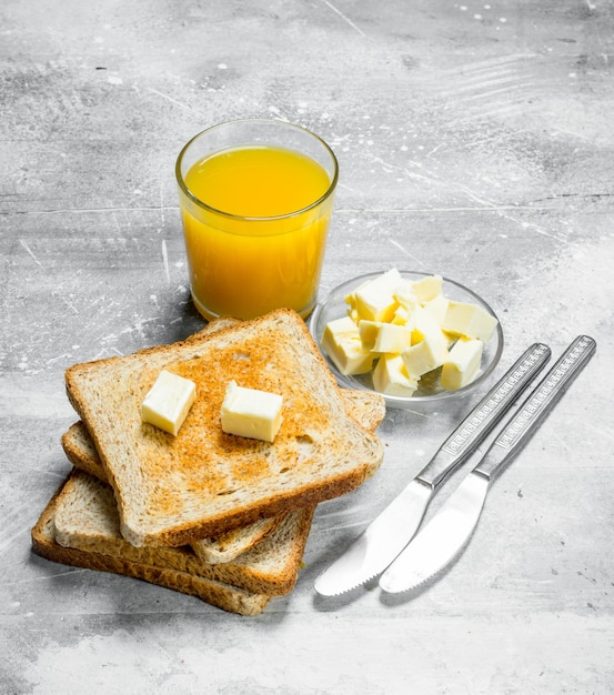 Breakfast toasted bread with butter and a glass of orange juice