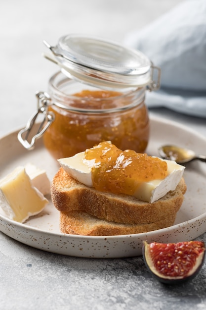 Breakfast toasts with brie cheese and fig jam on ceramic plate Healthy gourmet snack