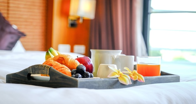 Breakfast in a tray on the bed in the luxury hotel room ready for tourist travel.