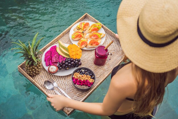 Breakfast tray in swimming pool floating breakfast in luxury hotel girl relaxing in the pool