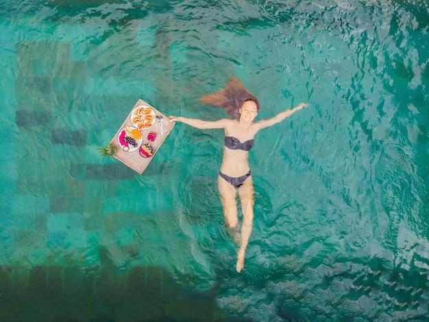 Breakfast tray in swimming pool floating breakfast in luxury hotel girl relaxing in the pool