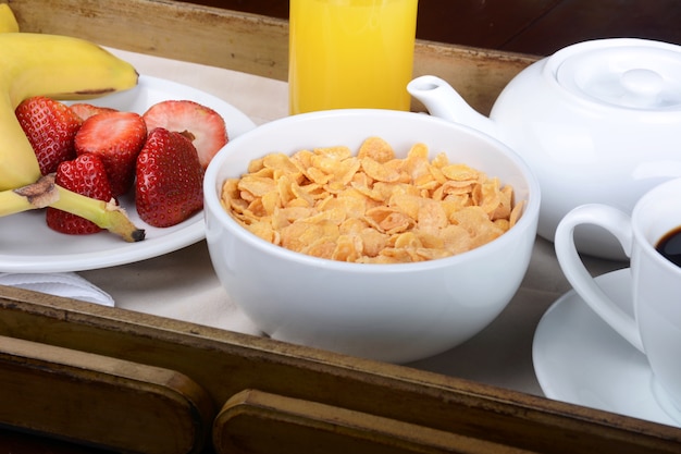 Breakfast tray with coffee, orange juice, cereals and fruits.