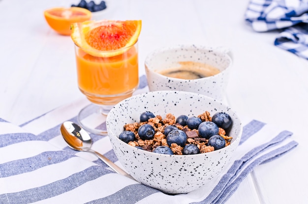 Breakfast on a white wooden background. Muesli with berries and orange juice. Copy space