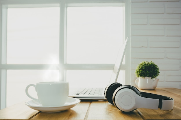 Фото Завтрак с чашкой теплого кофе на столе в офисе которого есть ноутбук.