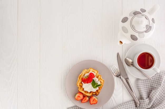 Prima colazione con cialde belghe su legno bianco