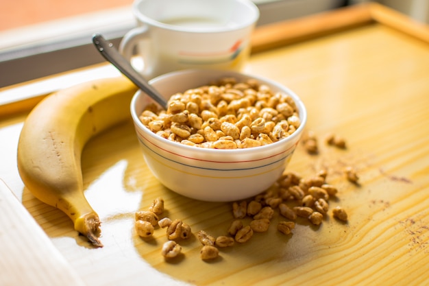 Breakfast with cereals in a bowl with milk, cocoa and banana