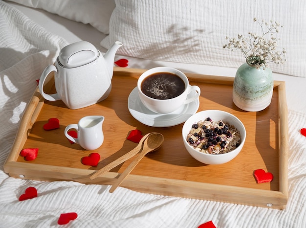 breakfast with coffee and muesli on a wooden tray with hearts on the bed