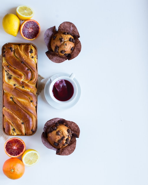 Breakfast with coffee and tea with different pastries and fruits on a white wooden table