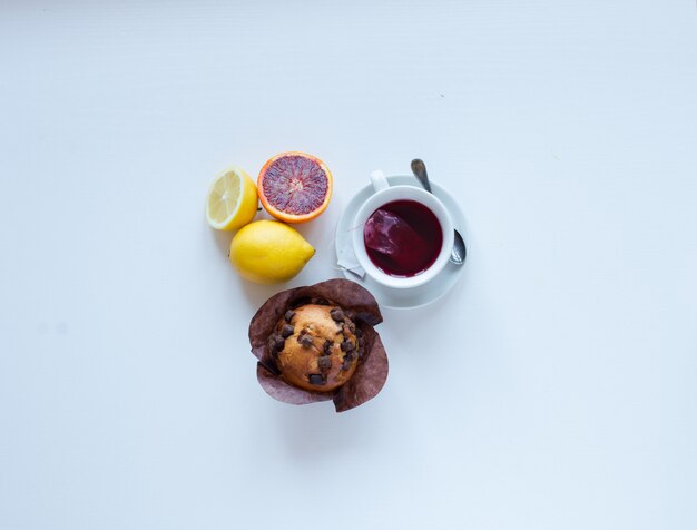 Foto faccia colazione con caffè e tè con differenti pasticcini e frutti su una tavola di legno bianca