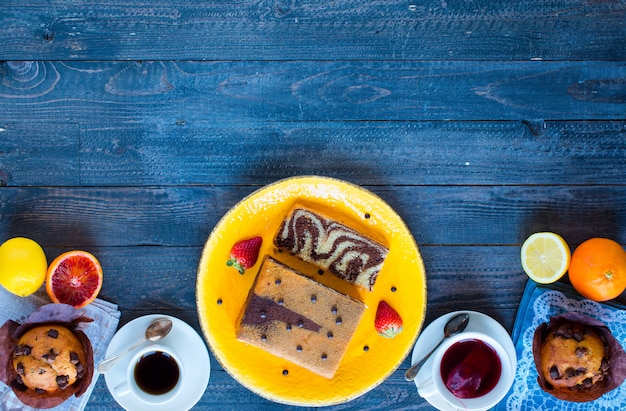 木製のテーブルにさまざまなペストリーや果物とコーヒーと紅茶を朝食します。