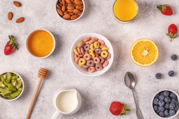 Colazione con anelli di cereali colorati, frutta, latte, succo di frutta