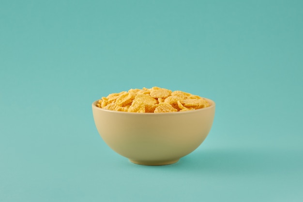 Foto colazione con cornflakes in una ciotola isolata su sfondo azzurro