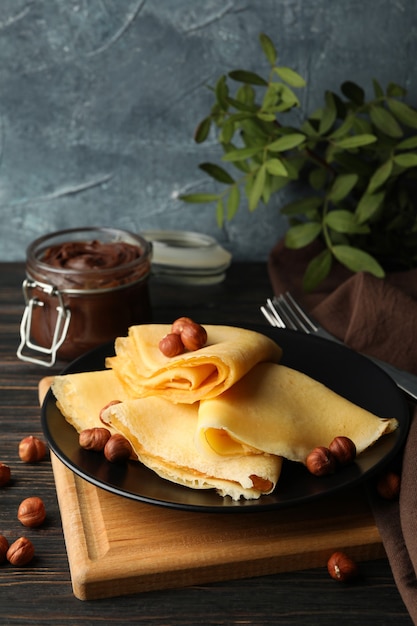 Breakfast with crepes with chocolate paste and nuts on wooden table