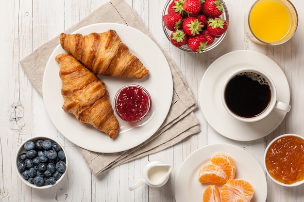 Breakfast with croissants, coffee, jam and berries