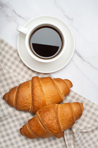 Breakfast with croissants and coffee mug on white marble background