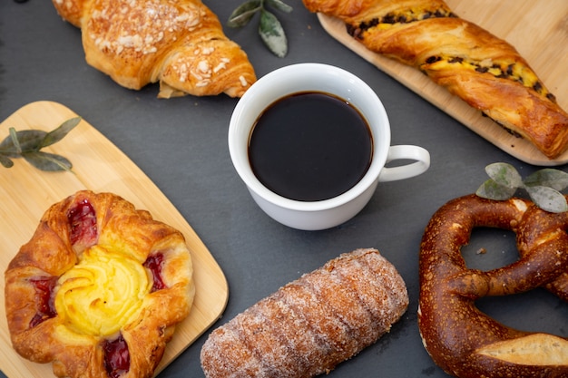 Breakfast with croissants, leaves, cutting board and black coffee on the morning breakfast.