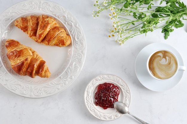 Breakfast with croissants, raspberry jam and cappuccino