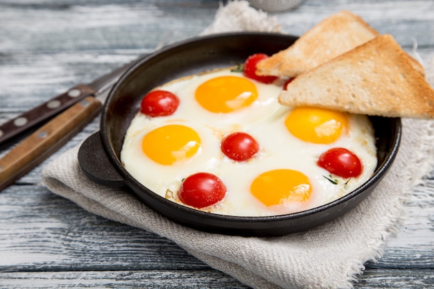 Breakfast with eggs, cherry tomatoes, bacon and fresh toasted toast