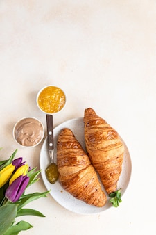 Colazione con croissant freschi, crema di cioccolato, marmellata e tulipani bella composizione romantica