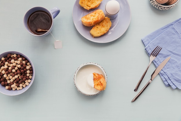 Breakfast with fried croutons yogurt and black tea on light wooden surface summer country food