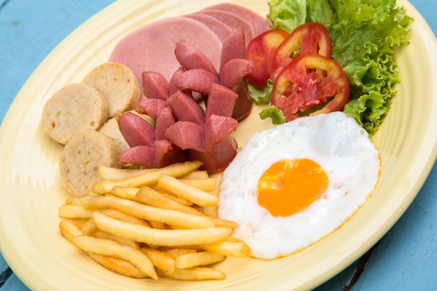 Breakfast with fried eggs, bacon, sausages,french fries